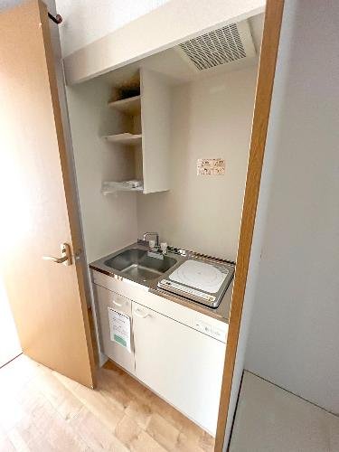 小さなキッチンエリア、シンクと電気コンロ、棚と換気扇付き