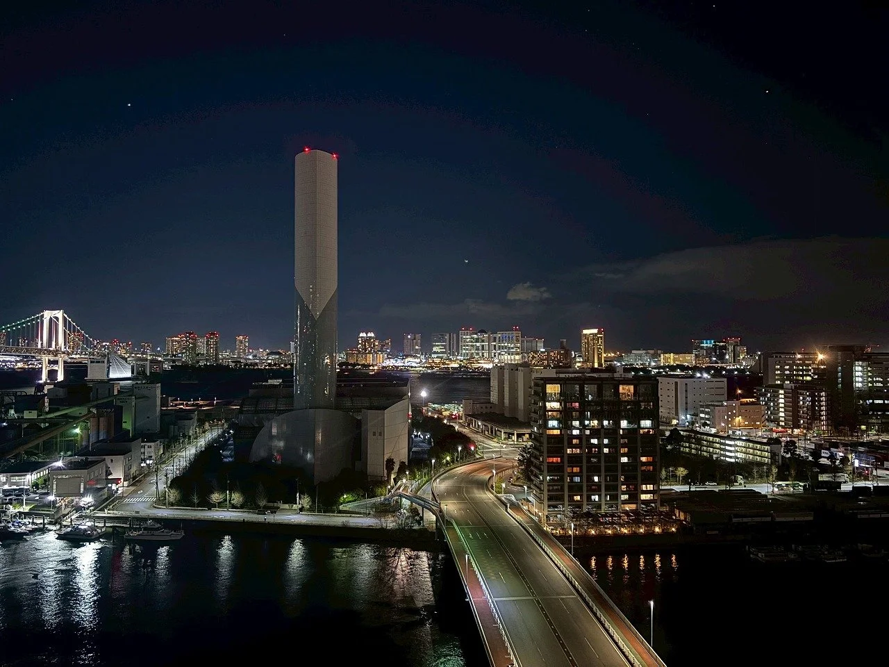 夜景の都市の風景で、高層ビルや橋、川が見える。空に星が輝いている。