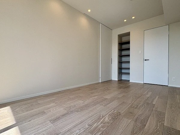 空の部屋の写真で、木製の床と白い壁、クローゼットとドアが見える。