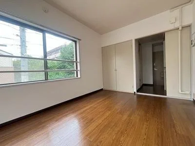 空の部屋で、木製のフローリングと大きな窓があります。