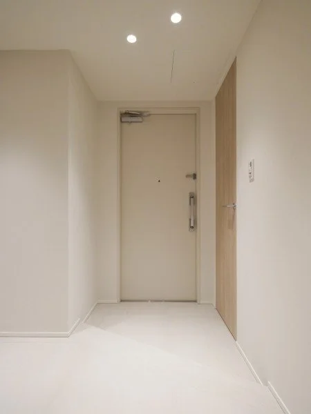 白い壁とドアがあるシンプルなエントランスホール