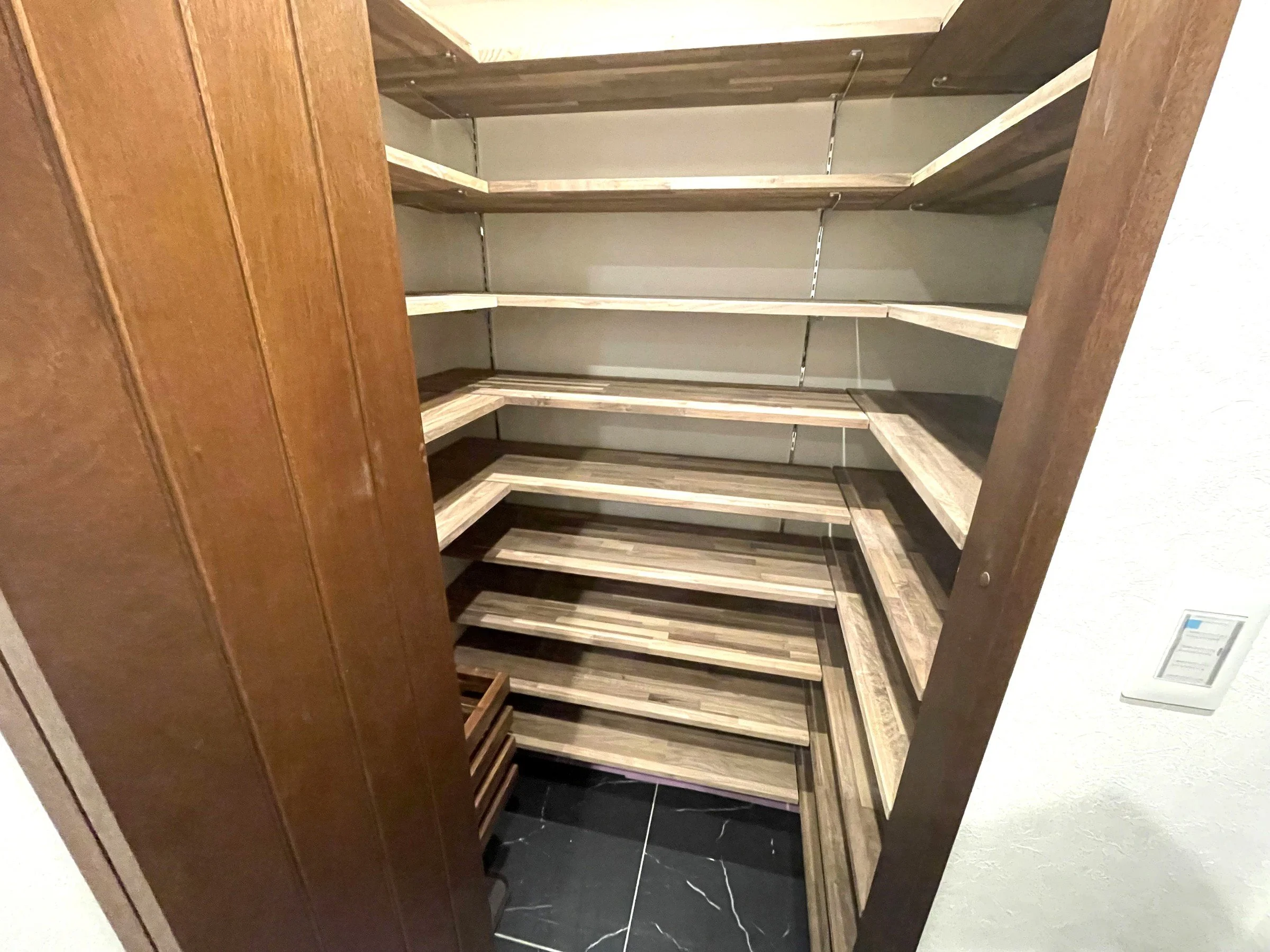 木製の棚が空いている店の棚、黒い床と白い壁が背景にある