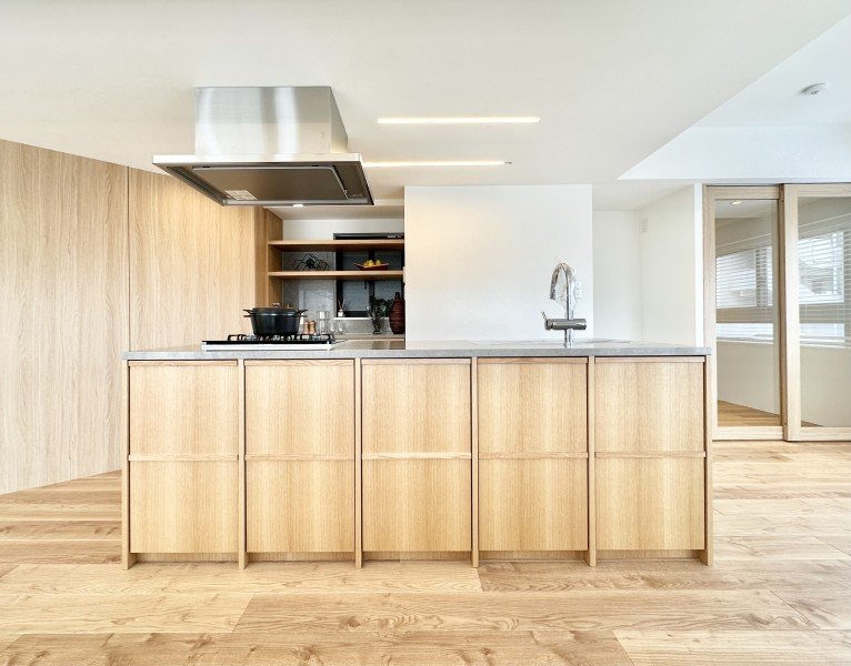 木製のキッチンカウンターとシンク、コンロ、換気扇が設置されたモダンなキッチンです