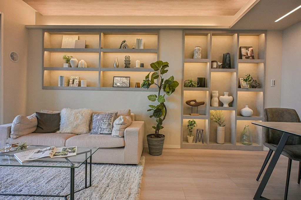 リビングルームに本棚とソファ、コーヒーテーブル、観葉植物が配置されている。