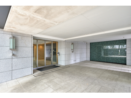 モダンな建物のエントランスエリア。ガラスドアと照明付きの壁があります。