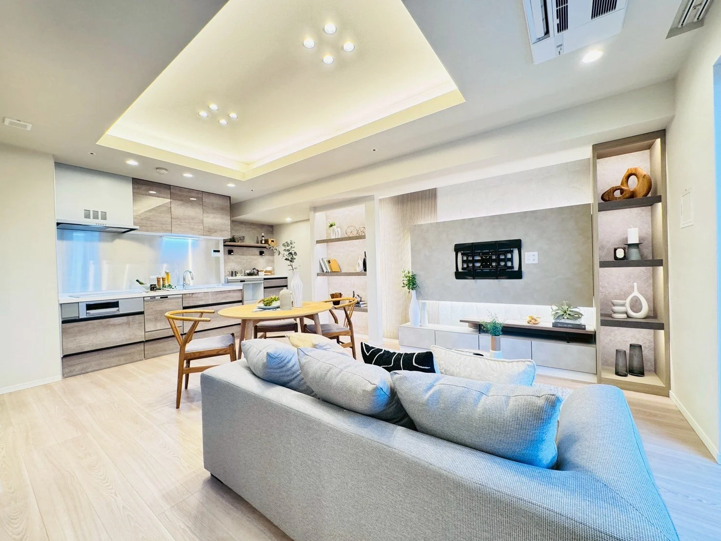 明るく広々としたリビングとキッチンダイニングルームのインテリア写真。ソファ、ダイニングテーブル、オープンキッチンが見えるシーン。