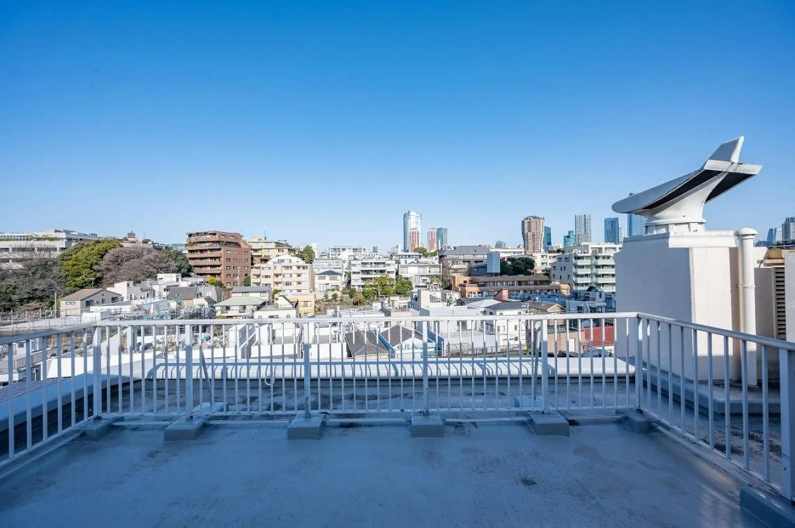 都心の屋上から見える都市景観。青空と高層ビル群、住宅街が広がる景色。