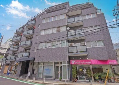 中層のマンションと地上の商店街の建物、青空と電線のある風景