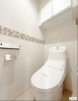 白いトイレと壁に飾られたタイル模様の壁紙があるトイレの室内