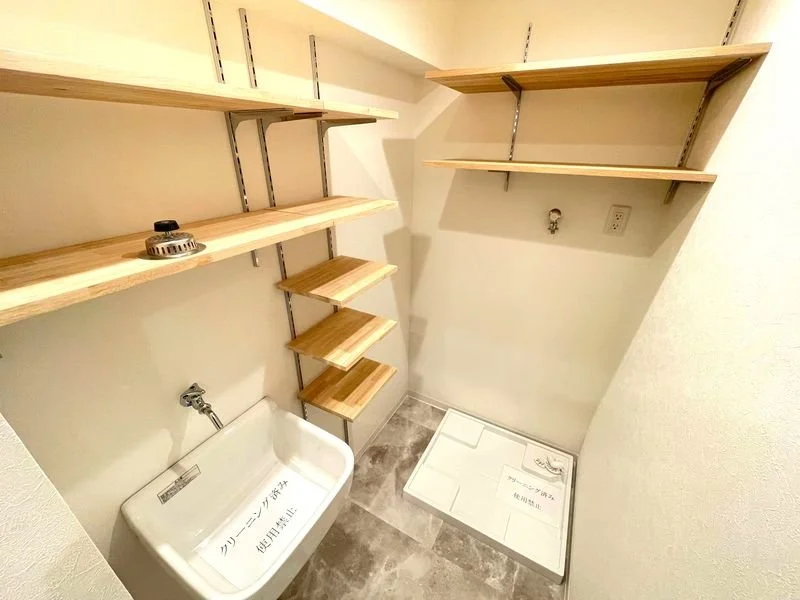 棚と洗濯機置き場、壁にコンセントと水道管がある、狭い部屋