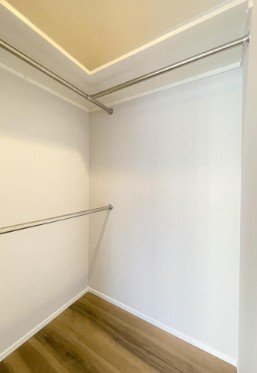 空のクローゼット内の白い壁と金属のハンガーパイプ、木の床