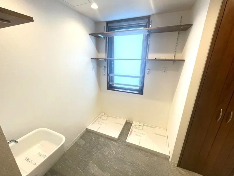 空の部屋で、窓のそばに棚と洗濯機置き場のスペースがある