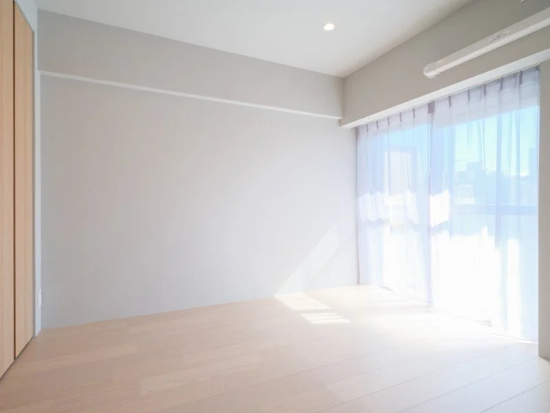 明るい日の光が差し込む、シンプルな空の部屋と白いカーテンの窓