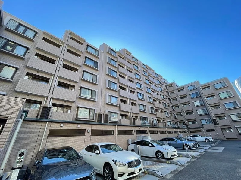多層のコンクリート製集合住宅と駐車場の写真