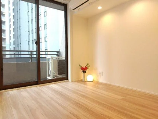 空の部屋、木製のフローリングと窓、外の建物とバルコニー、花とライトの飾り