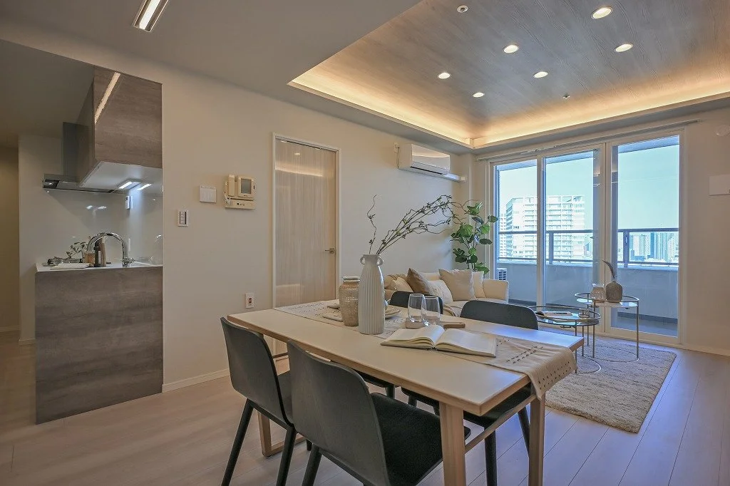 リビングルームとダイニングルーム、キッチンが見える広々としたマンションの内装。大きな窓から自然光が入る。