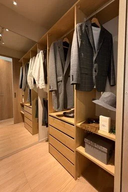 クローゼットの棚に、スーツやシャツ、ジャケット、帽子、本、箱などが整理されている