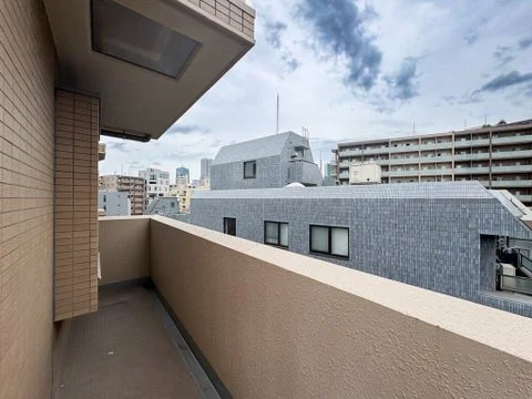 高層ビルのある都市のバルコニーからの眺め、青空と雲が見える