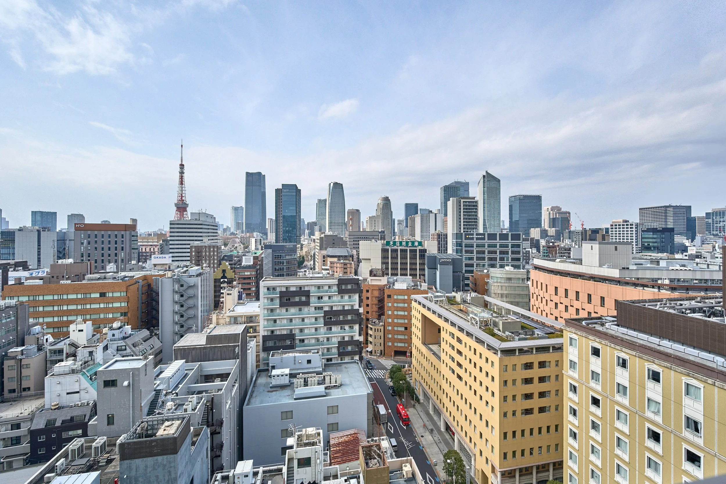 東京の都市の景色で、多くの高層ビルと薄い青い空が広がっている。