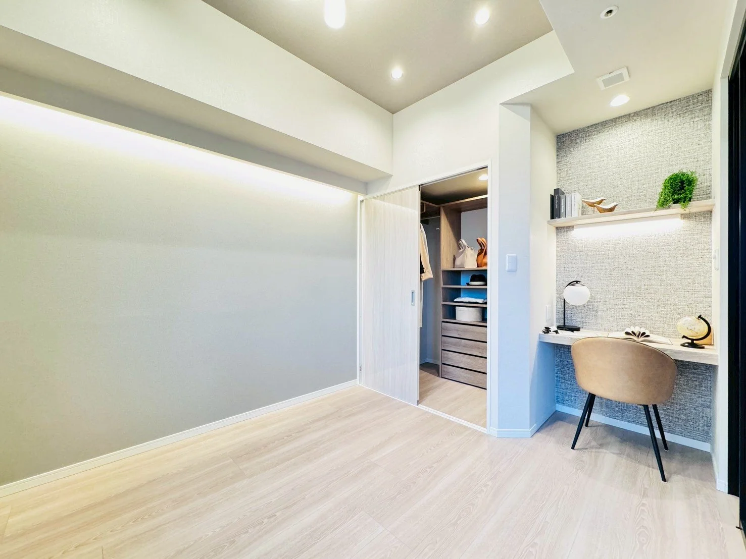 シンプルでモダンなワークスペースとクローゼットがある明るい室内の写真