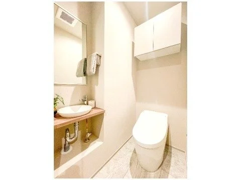 白い壁とトイレ、棚と鏡がある小さなトイレルーム