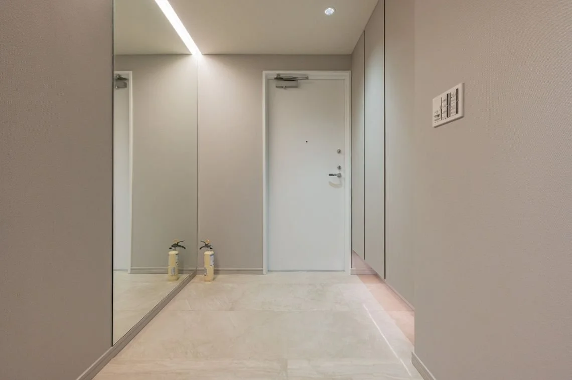 白いドアと壁、鏡、2本の消火器が置かれたモダンな廊下の interior image