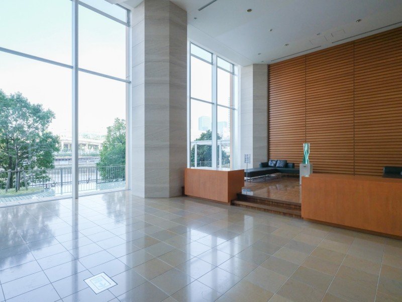 明るいロビーに大きな窓と木製の壁、ソファと飾りの置物が配置された空間