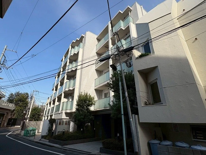 白い多階建ての建物と電柱、電線が空に伸びている風景。