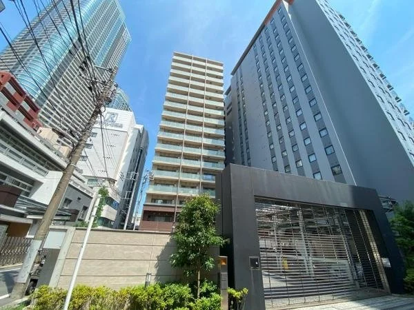 高層ビルが立ち並ぶ都市の景色。青空とともに、ガラス張りの建物や電柱も見える。