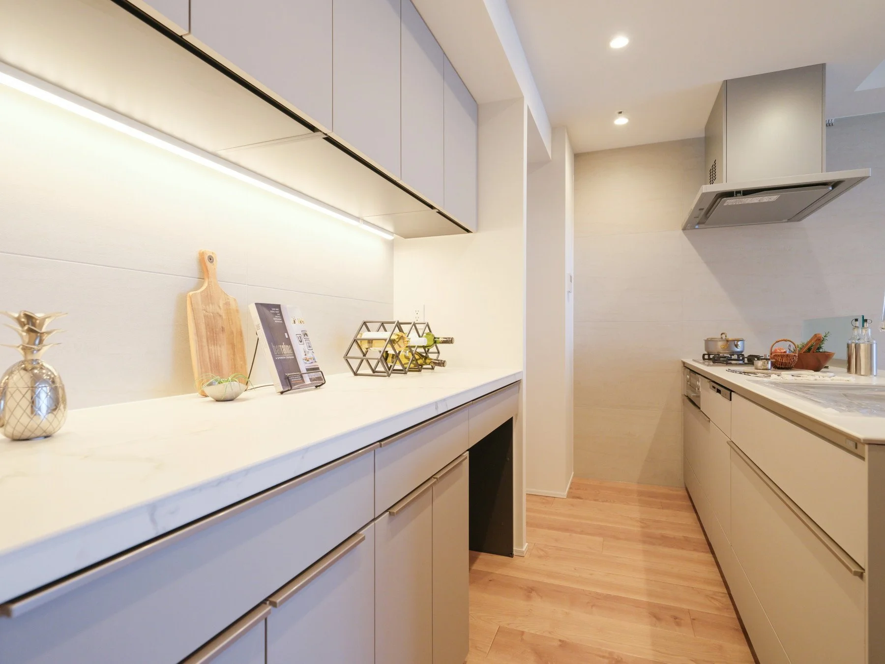 白いキッチンカウンターと調理器具、装飾品が配置されたシンプルなキッチン空間