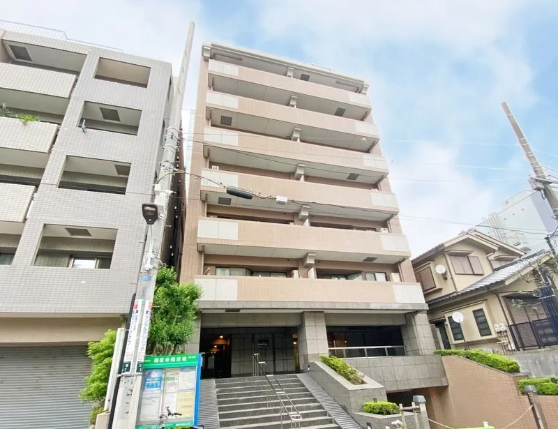 高層マンションの外観と階段部分。周囲に電柱と電線が見える。