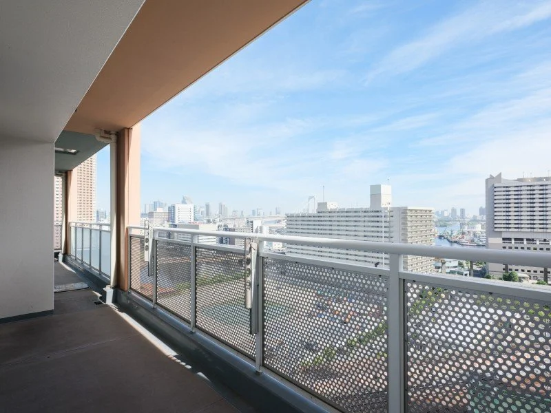 マンションのバルコニーから見える都市の景色。青空と高層ビル群。