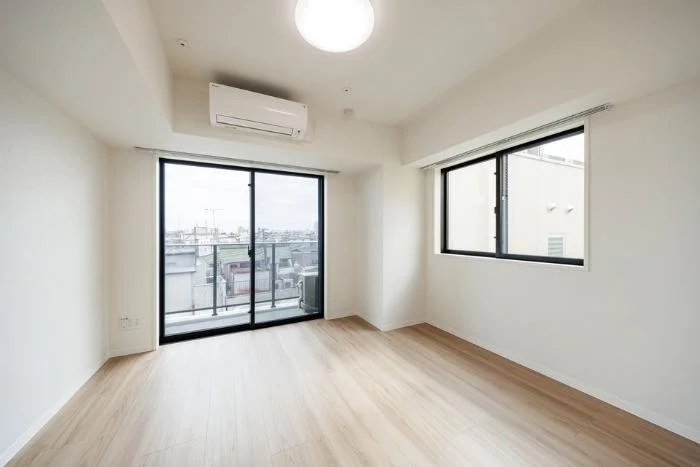 白い壁と木の床の空き部屋、窓とバルコニーのある明るいリビングルーム