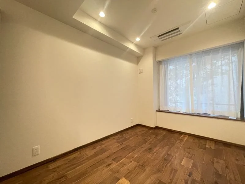 空の部屋で木製の床、白い壁、大きな窓にカーテン、天井に照明