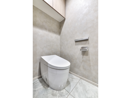 トイレとトイレットペーパーホルダーがついたシンプルなトイレルームの壁と床