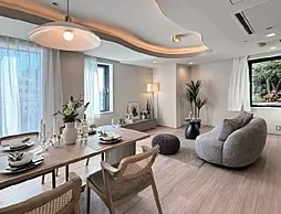 白を基調としたリビングルームとダイニングエリア、ソファとダイニングテーブル、窓からの自然光と観葉植物が配置されている明るい空間