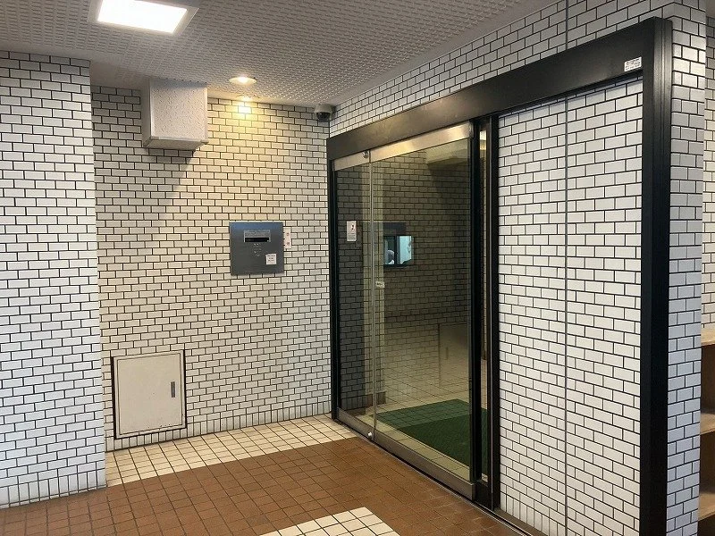 白いタイル張りの壁とガラス扉のエレベーターの入口