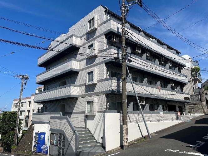 多層のコンクリート製の建物と電柱と電線がある風景、青空の下にあります
