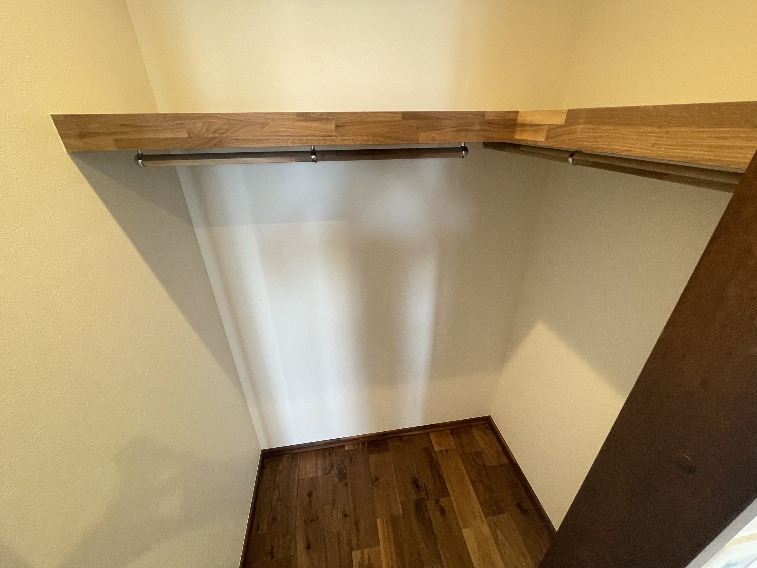 収納庫の内部、木製の2本のハンガーバーと棚が付いている