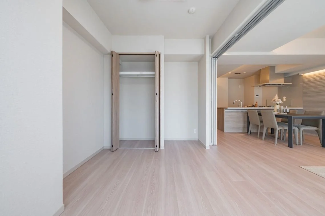 白い壁の部屋で、開いたクローゼットとダイニングルームが見える