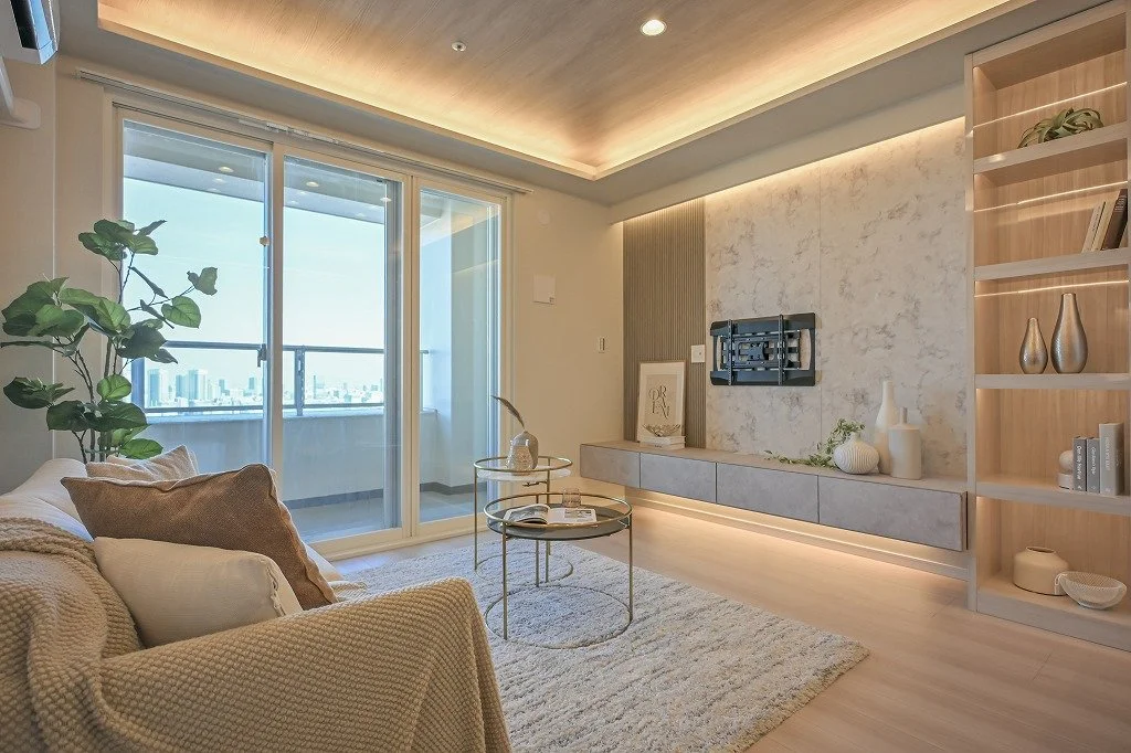 明るいリビングルームで、ソファ、ガラスのコーヒーテーブル、観葉植物、大きな窓から都市の景色が見えるデザインの室内