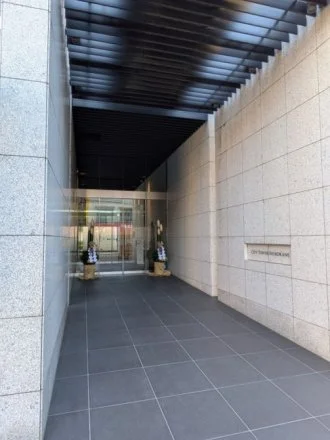 現代的な建物のエントランス、両側に花のついたプランターが置かれている