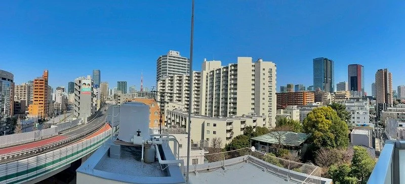 都市の高層ビルと橋が見える都市景観。青空が広がる晴れた日。