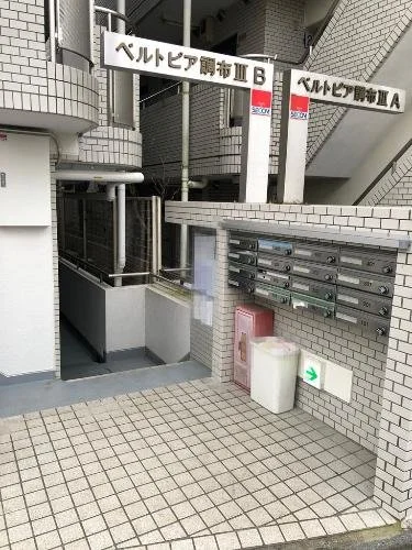 ビルの外に設置された郵便ポストとメール箱。階段とビルの壁が見える。