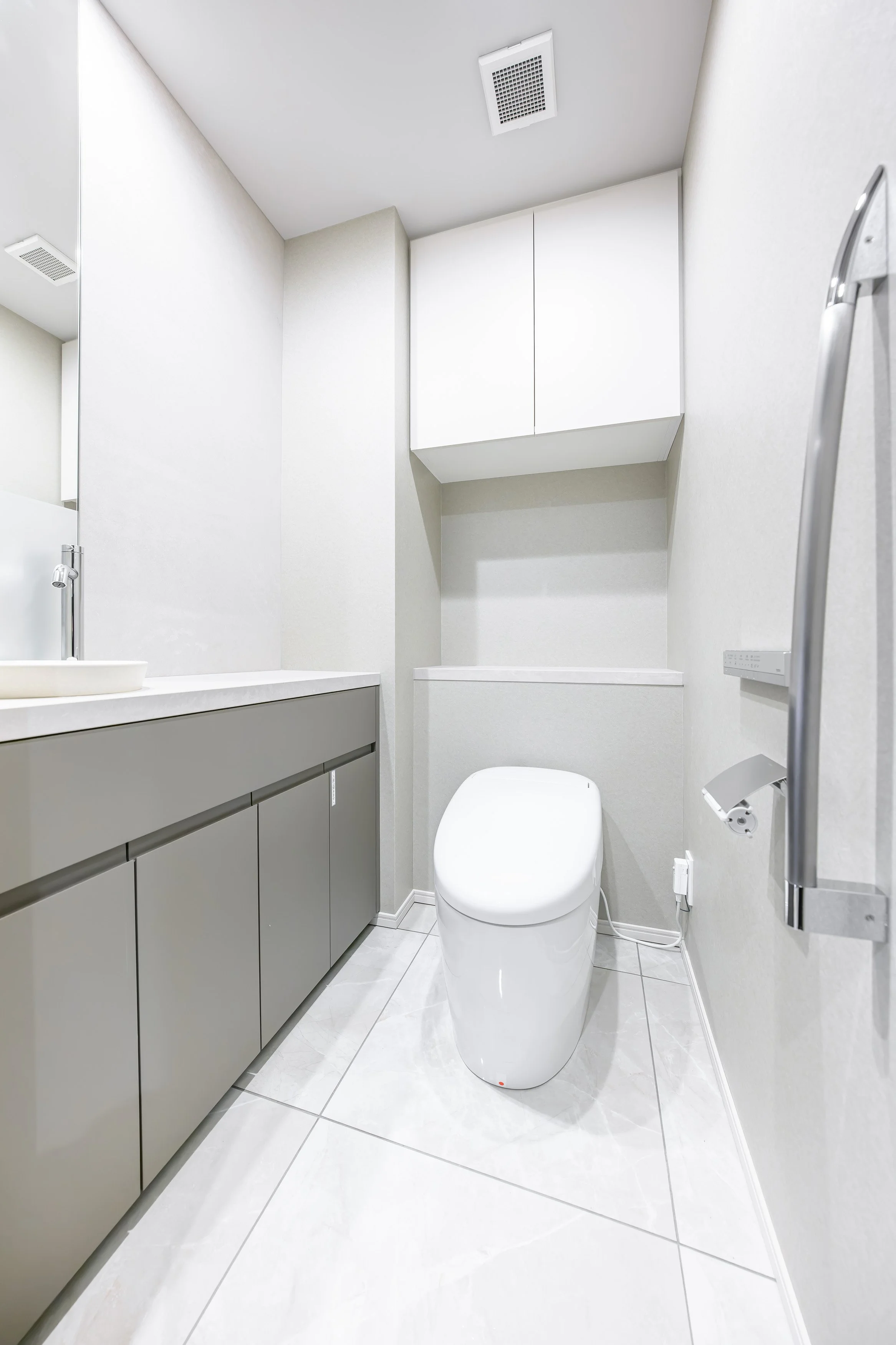 白いトイレと洗面台のあるシンプルで清潔なトイレルーム.