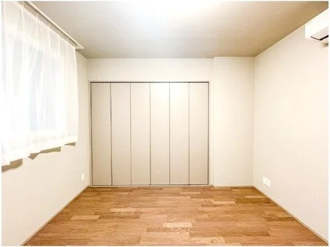 空の部屋、木製フローリングと白い壁、窓にはカーテン。