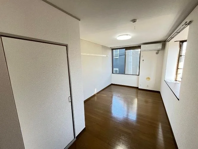 空の部屋、白い壁と木製の床、窓からの自然光、天井に照明