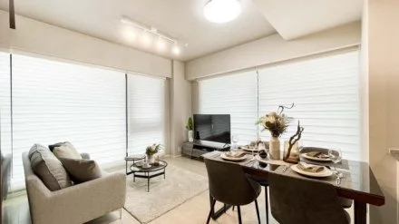 リビングルームの Interior with sofa, TV, dining table, and windows with blinds.
