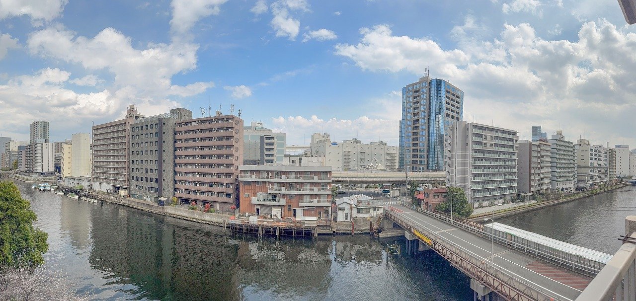 川沿いの都市景観、複数の高層ビルと橋と空が見える