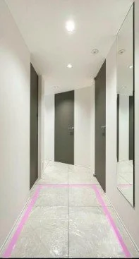 エレベーターの前の通路、鏡と閉まった扉が見える明るいスペース